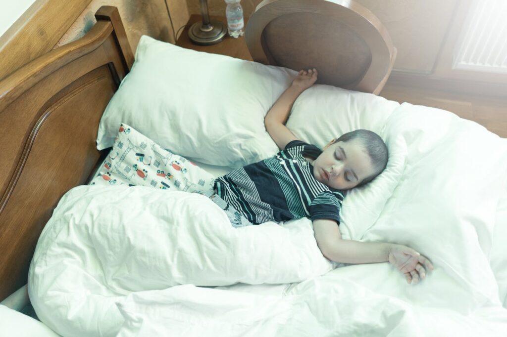 A young boy peacefully sleeping in a cozy bed surrounded by pillows and blankets.